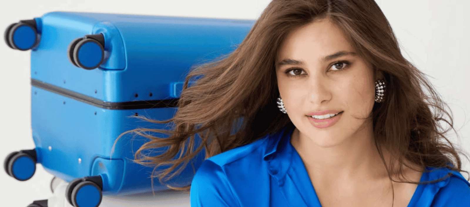 Suitcase, young woman with flowing hair and blue outfit, travel, stylish traveler, luggage, fashion accessory, journey, travel lifestyle, blue suitcase, smiling woman.
