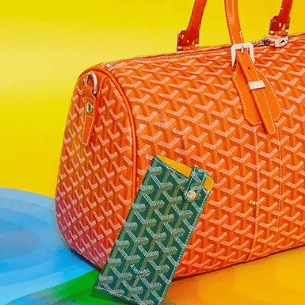 Vibrant orange designer tote bag with signature pattern and matching smartphone case on colorful background.