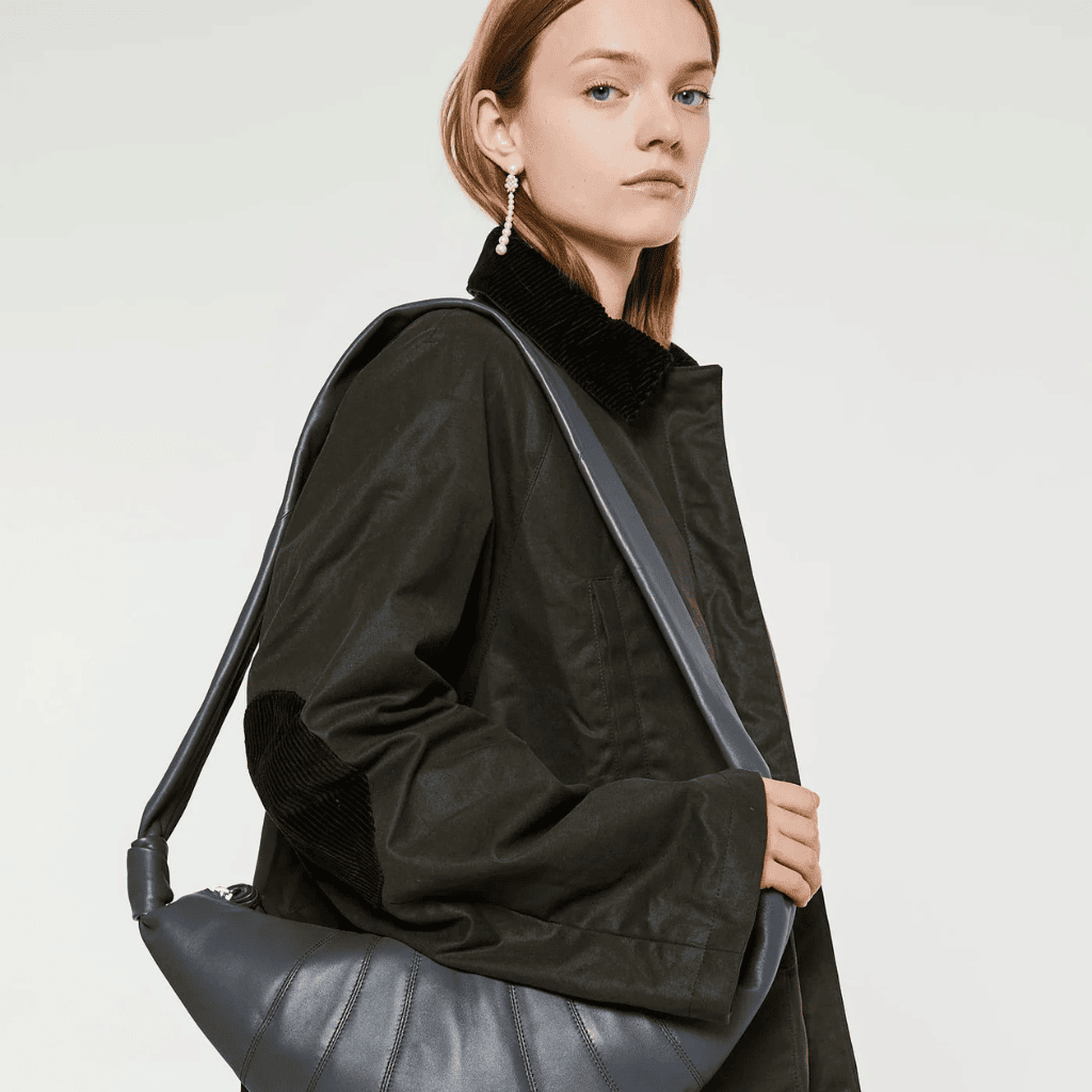 Black leather shoulder bag with sleek design and stylish casual outfit.