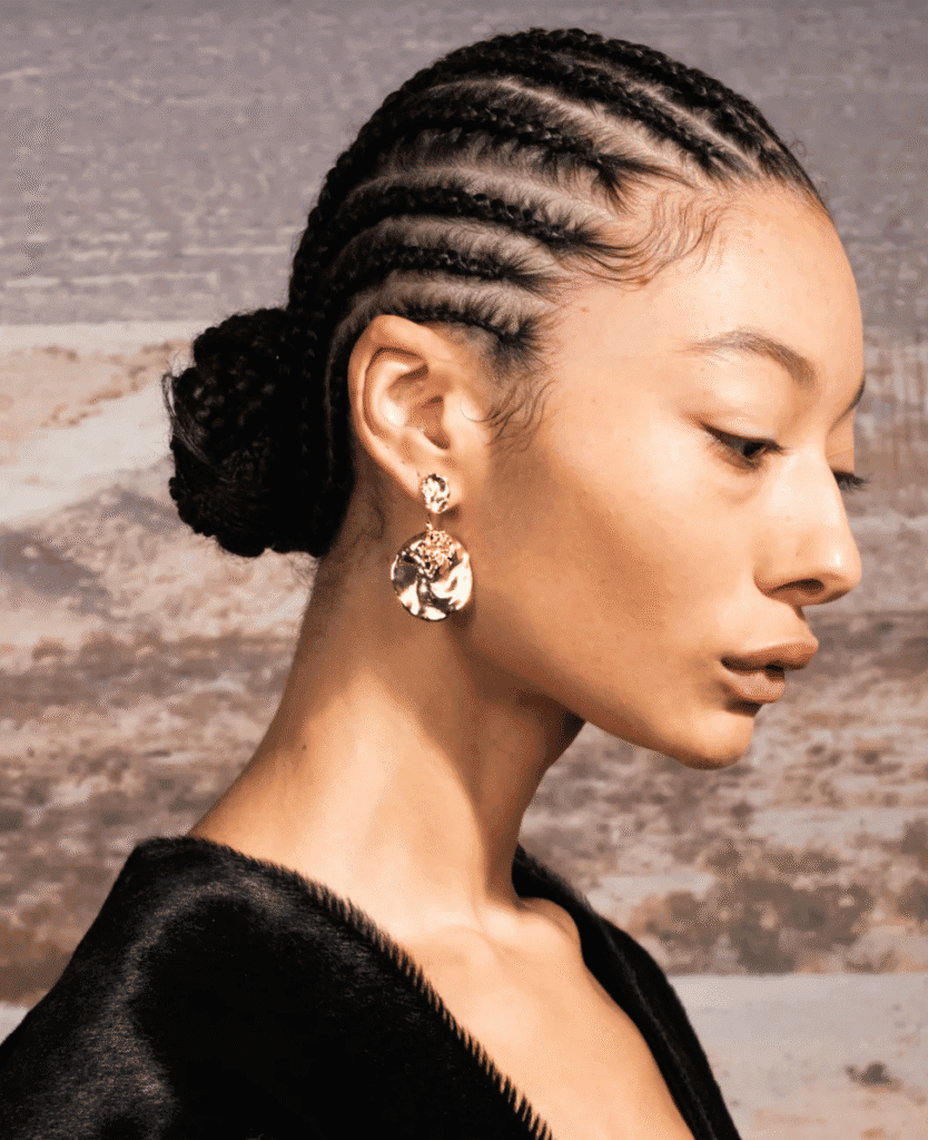 Braided hairstyle with elegant earrings and black velvet outfit for stylish look.