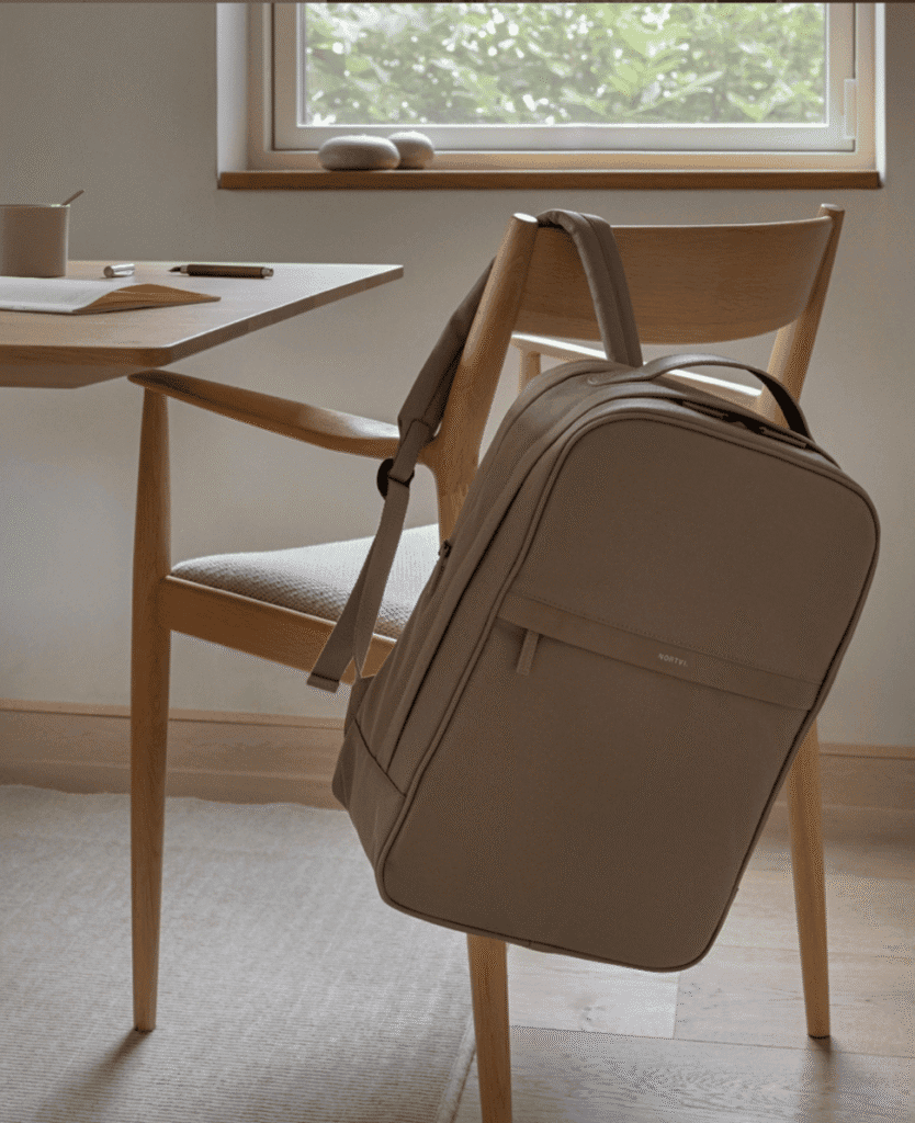 Soft beige backpack on wooden chair with neutral home decor emphasizing comfort and style.