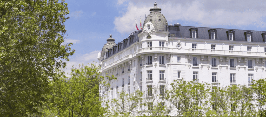 Lush Collective boutique hotel, elegant white building with classic architecture and lush green trees.