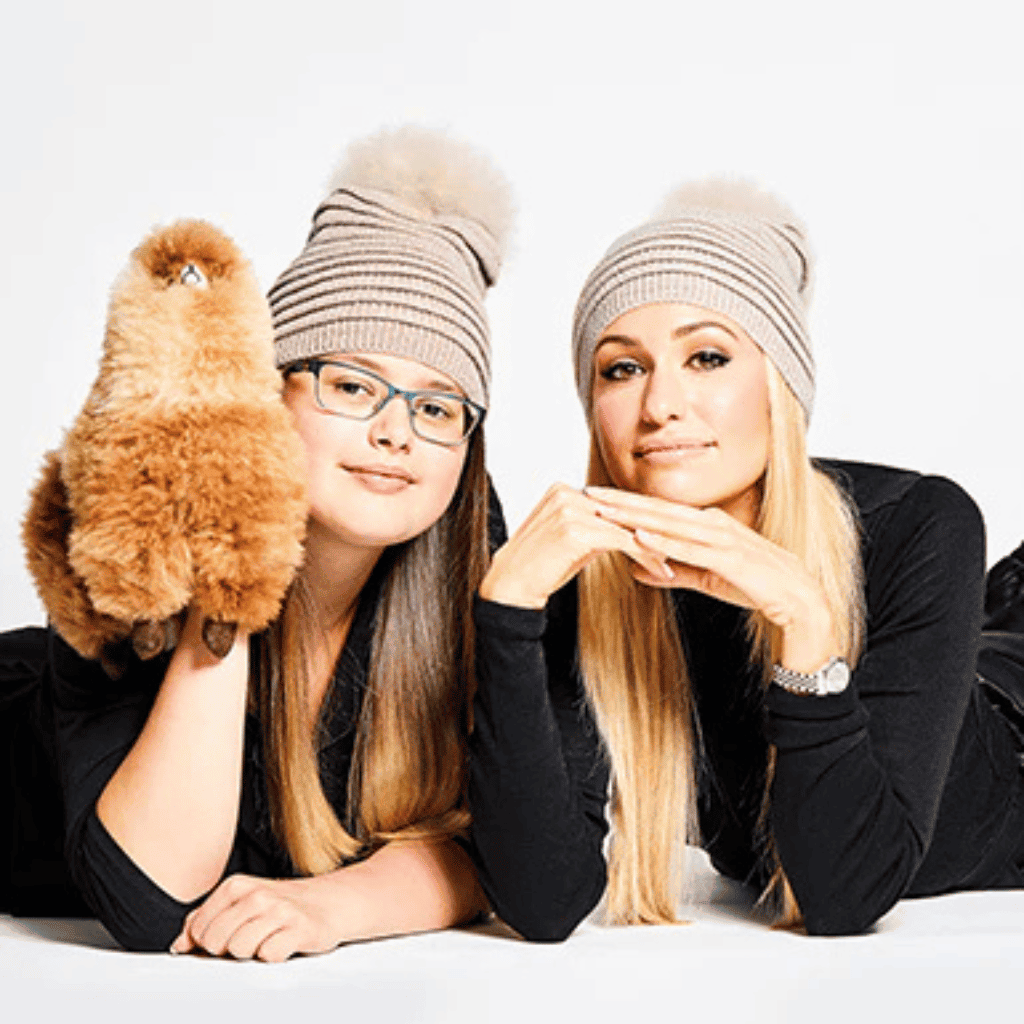 Fluffy Pomeranian dog and two women in cozy winter hats, stylish and trendy winter fashion.