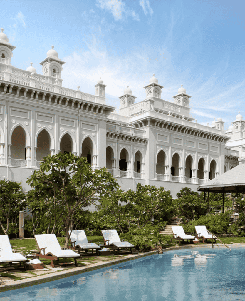 Luxury white palace exterior with pool and lush greenery in the foreground.