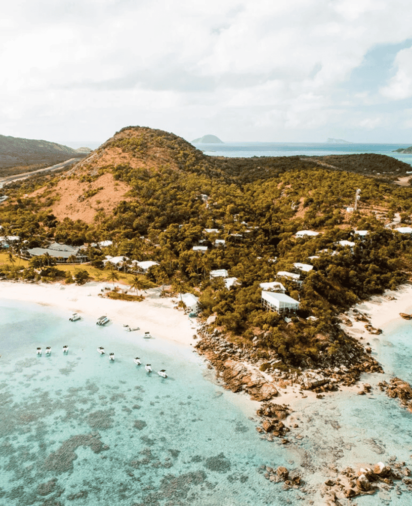 Secluded beach with clear turquoise waters and lush tropical hillside scenery at Lush Collective.