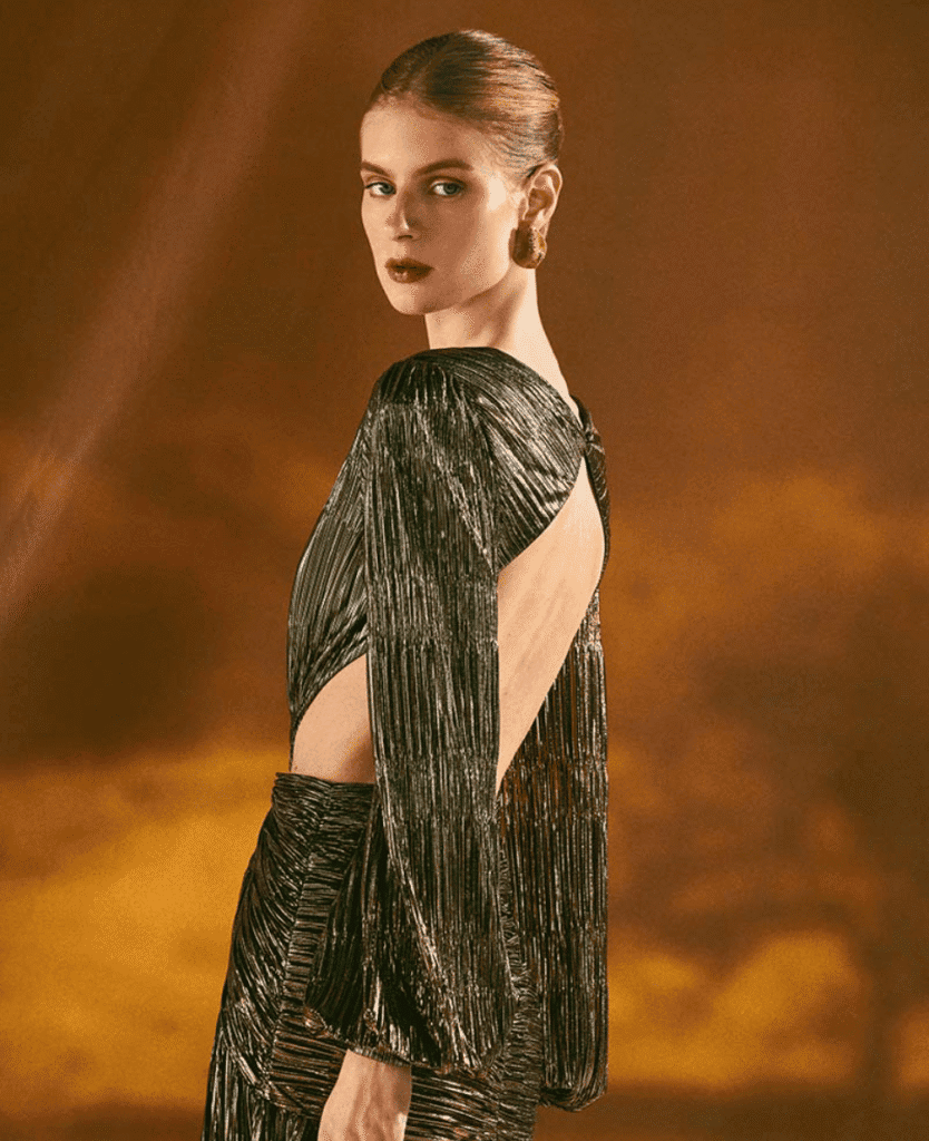 Radiant woman in glamorous metallic dress with open back for luxury fashion and beauty.