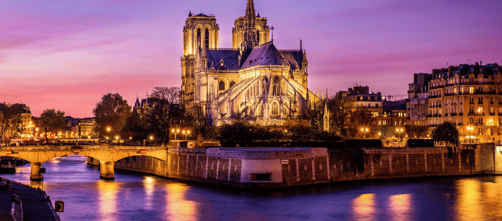 Refined gothic cathedral illuminated at sunset along the Seine River in Paris, France.