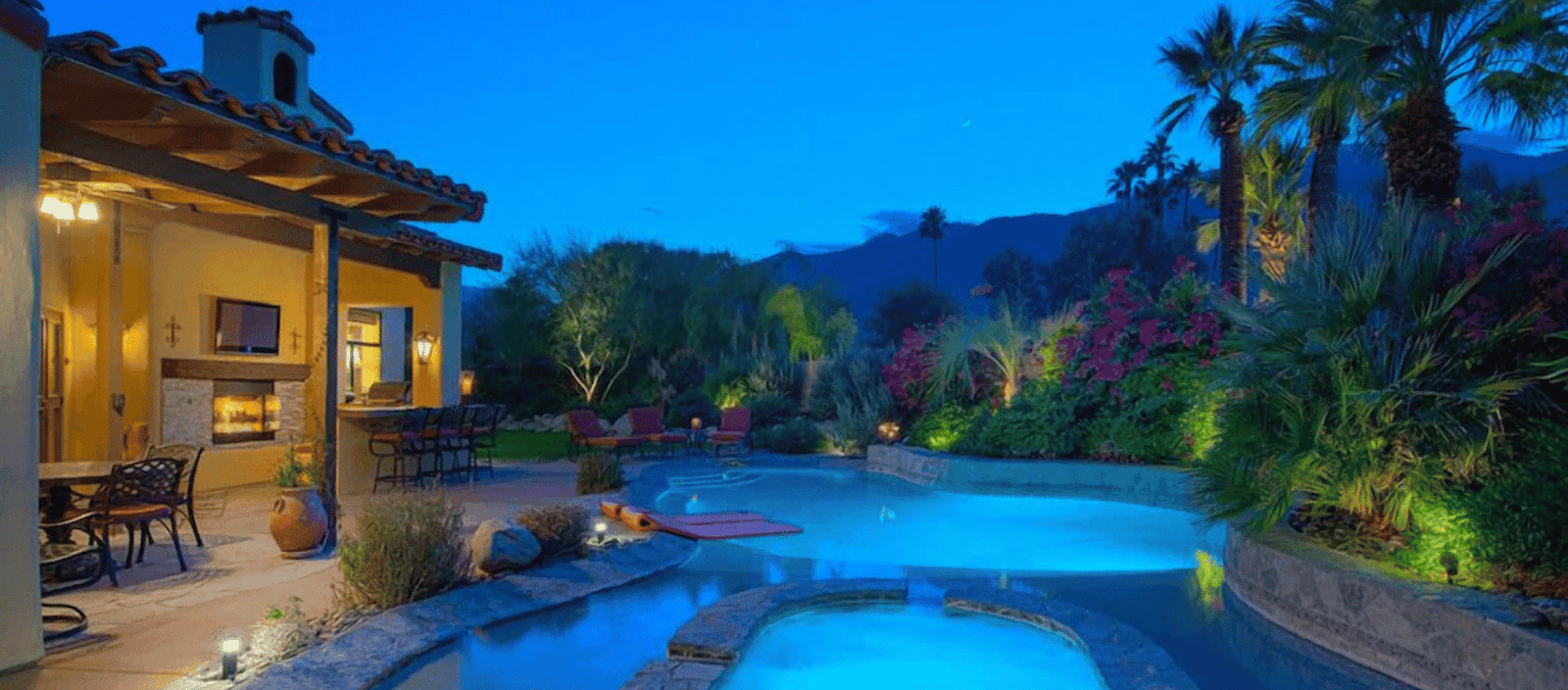 Luxurious backyard with heated swimming pool and ambient lighting in a beautiful desert landscape.