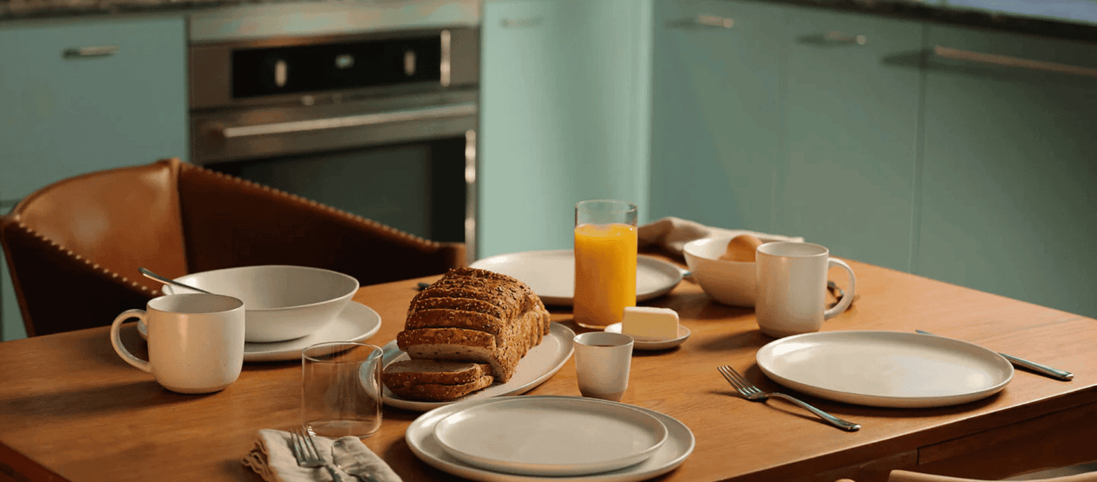 Sourdough bread breakfast table with orange juice and cups, Lush Collective home dining setup.