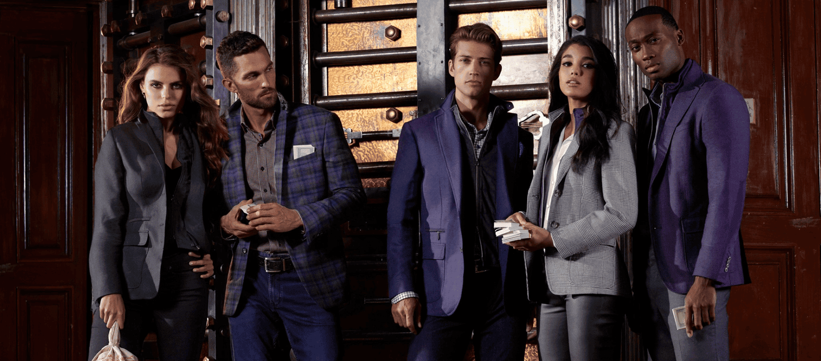 Luxury fashion models in stylish suits standing indoors for fashion shoot.