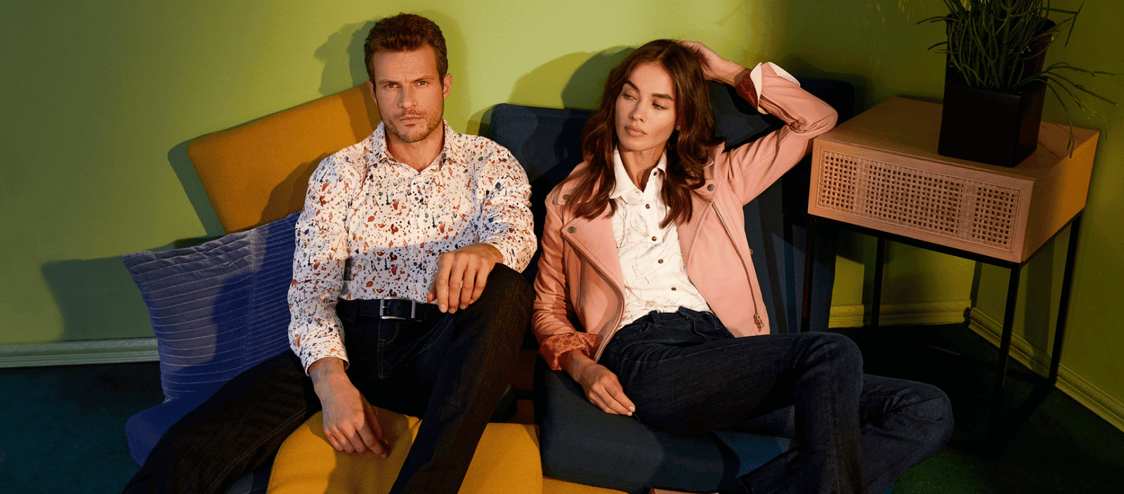 Colorful modern lounge with stylish man and woman relaxing on vibrant sofa.