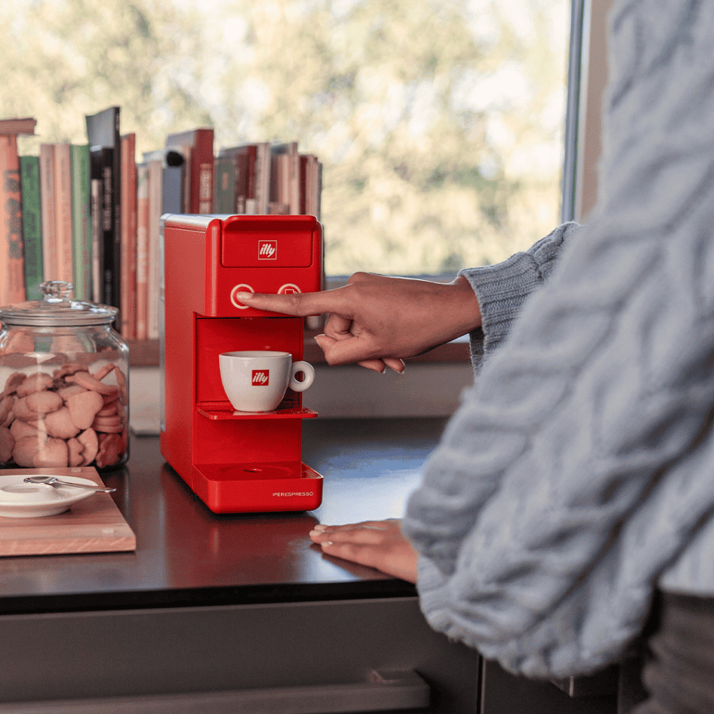 Red illy espresso coffee machine brewing a cup of coffee at home.