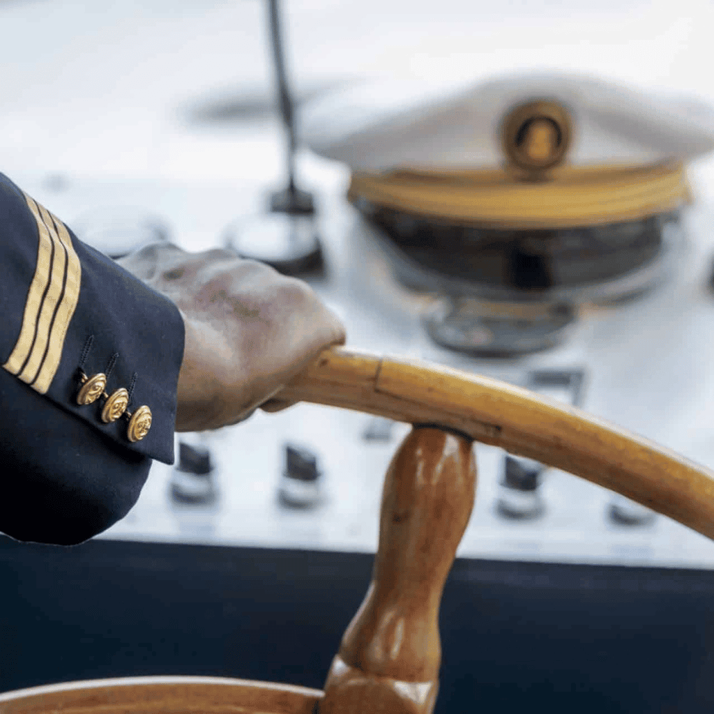 Elegant chef in navy uniform stirring a large wooden bowl in a modern kitchen with gas stove.