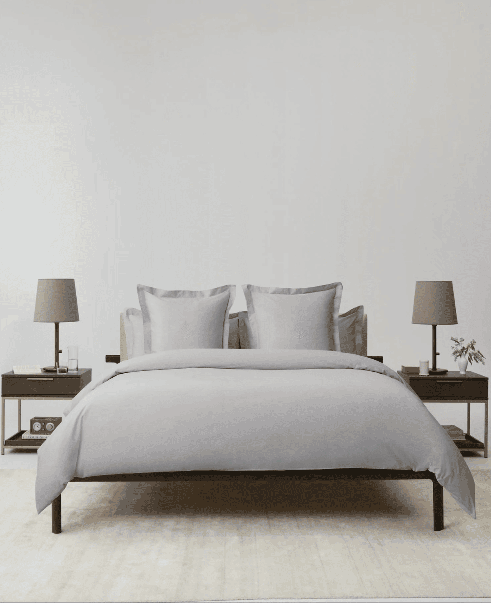 Bed with white bedding and matching pillows in a minimalist bedroom setting.