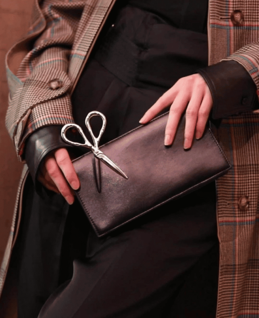 Scissors on black clutch purse, fashion accessory, stylish handbag, metallic scissors, elegant accessories.