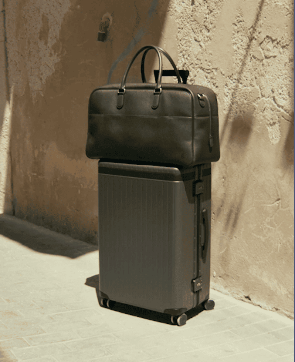 Leather travel bag on top of a black suitcase, minimalist travel accessories.