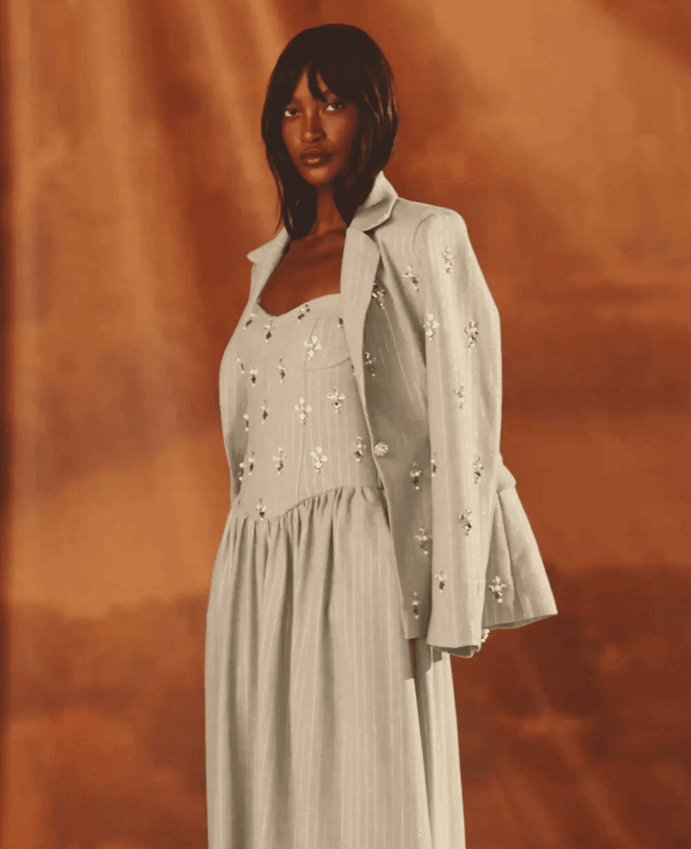 Luxury fashion model wearing elegant embroidered dress and blazer, stylish clothing, high-end apparel, fashion photography.