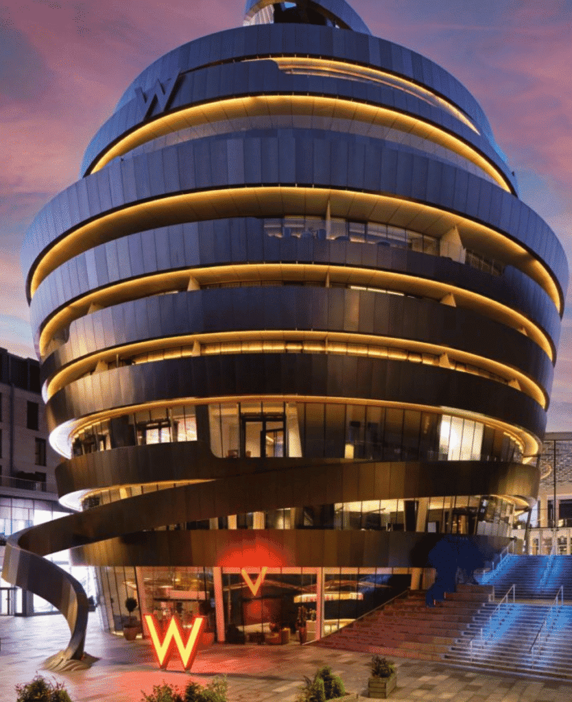 Modern futuristic building with spiral gold accents, illuminated at dusk, innovative architecture by Lush Collective.