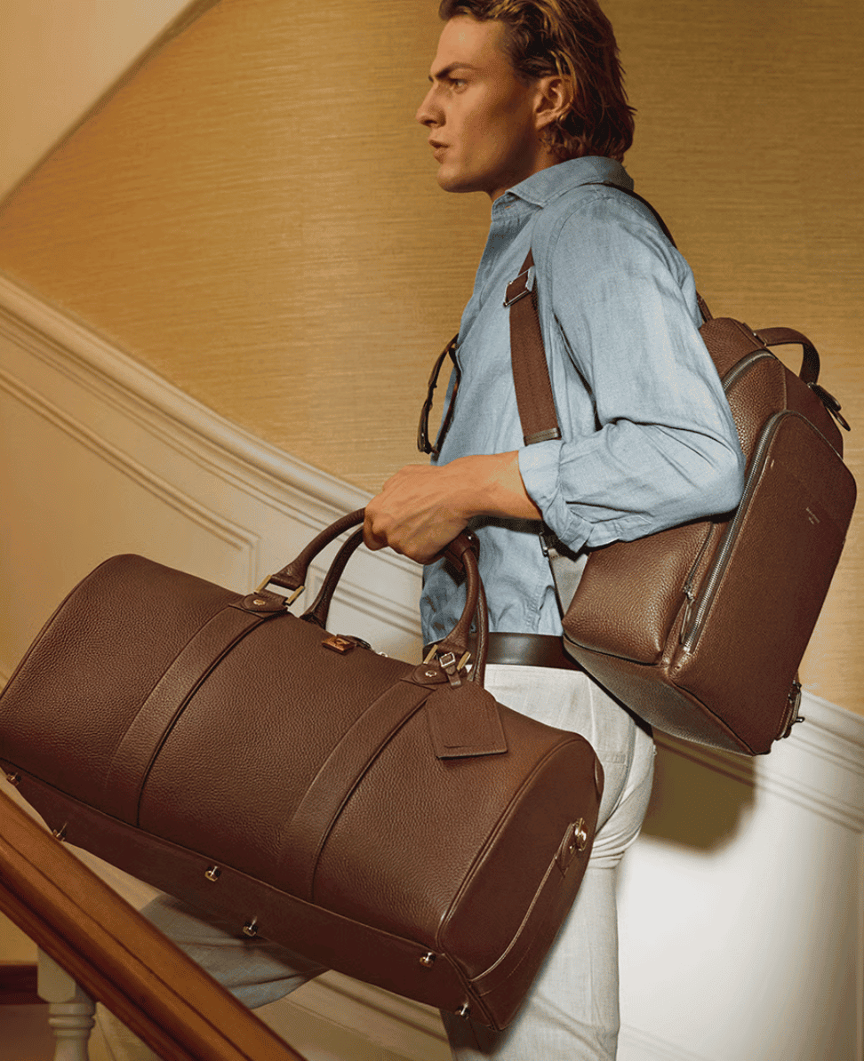 Duffel bag and backpack on a man dressed in casual attire.
