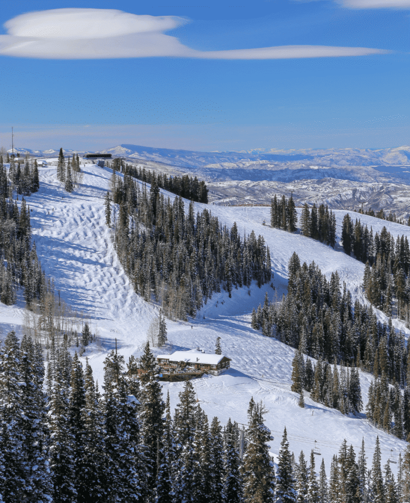 Powder snow-covered ski slopes in a scenic mountain landscape with evergreen trees and a cozy lodge, perfect for winter sports and mountain adventures.