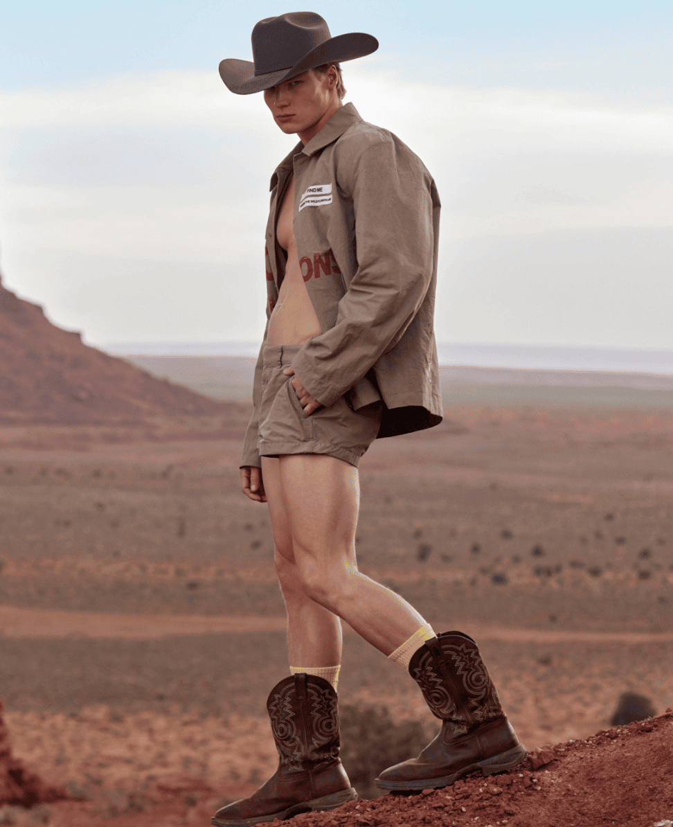 Fashion model wearing cowboy hat and rugged outdoor clothing at desert landscape, stylish and adventurous look for outdoor fashion.